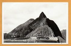 an old black and white photo of a car parked in front of a large mountain