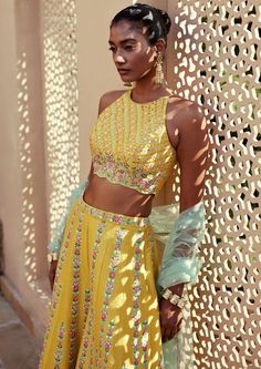 Yellow dupion silk resham and mirror work embroidered pants and incut shoulder top paired with contrast tulle dupatta. Summer Designer Pant Set With Dupatta, Sleeveless Sets With Sheer Dupatta For Festivals, Organza Choli With Mirror Work, Summer Silk Sharara With Traditional Drape, Designer Silk Pant Set For Summer, Summer Silk Palazzo Set With Resham Embroidery, Cotton Silk Sets With Gota Work For Reception, Silk Palazzo Set With Sequins For Festivals, Designer Yellow Sequin Sets