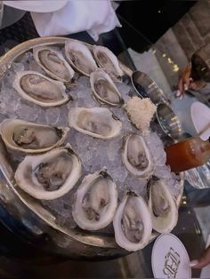 a platter filled with oysters on top of ice and silver serving utensils