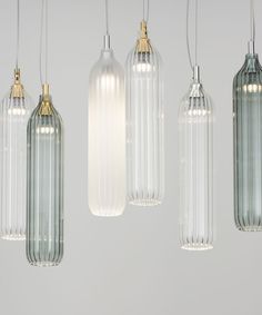 five glass pendants hanging from the ceiling in various shapes and sizes, each with one light bulb turned on