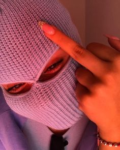 a woman wearing a purple mask with her finger on the nose and fingers pointing at it