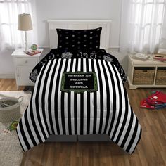 a black and white striped bed in a room with wooden floors, two nightstands and a lamp