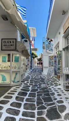 an alley way with shops and flags on the buildings in the background, surrounded by stone walkways