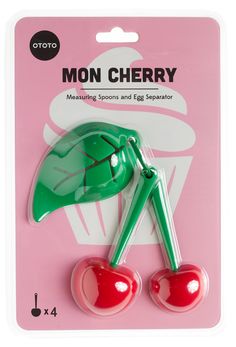 a pair of green cherries sitting on top of a pink package with the words mon cherry