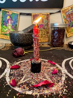 a lit candle sitting on top of a table covered in confetti