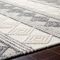 a white and gray rug on top of a wooden floor