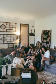 a group of people sitting on top of a couch in a living room next to each other