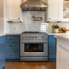 a stove top oven sitting inside of a kitchen next to white cupboards and wooden floors