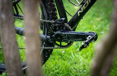 the bike is parked in the grass near some tree trunks and branches with chains attached to it