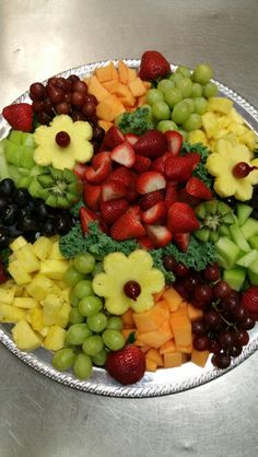 a platter filled with fruits and vegetables on top of a metal tableclothed surface