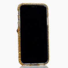 an old cell phone is covered in gold and diamond beads on a white surface with reflection