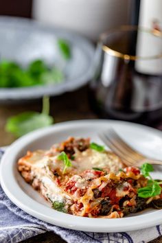 a white plate topped with lasagna covered in cheese and sauce next to a fork