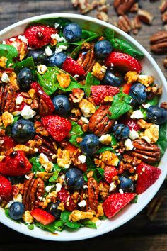 a white bowl filled with fruit and nuts on top of a wooden table next to pecans