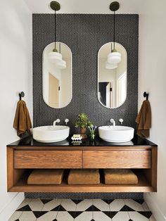 a bathroom with two sinks and mirrors on the wall next to a black and white tiled floor