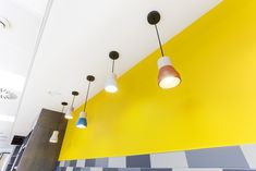 the lights are hanging from the ceiling in the kitchen area, with yellow and blue walls