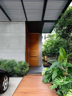 a car parked in front of a house with trees and plants on the side walk