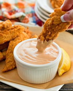 the dipping sauce is being poured onto chicken tenders