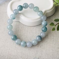 a bracelet with blue glass beads sitting on top of a table next to a potted plant