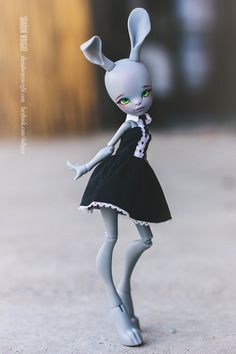 a doll is dressed in a black and white dress with an adorable rabbit ears headpiece