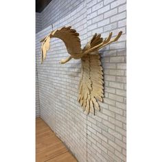 an eagle sculpture on the side of a white brick wall next to a wood floor