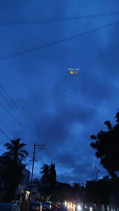 an airplane is flying in the sky above some cars and power lines at night time