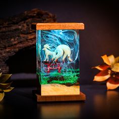 a glass case with an image of two horses in the water and plants behind it