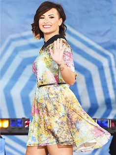 a woman in a short dress standing on a stage with her hand up to the side