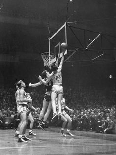 an old black and white photo of men playing basketball