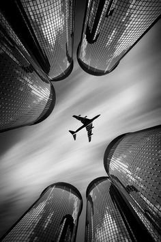 an airplane flying through the air between tall buildings