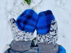 someone wearing blue mittens standing in the snow