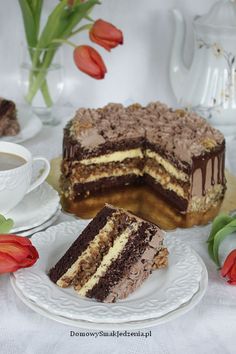 a piece of cake on a plate next to a cup and saucer with tulips in the background