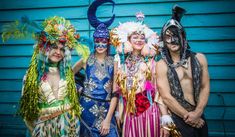 three men and two women dressed up in colorful costumes posing for a photo with each other