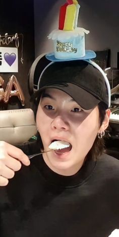 a woman brushing her teeth in front of a birthday cake on top of her head