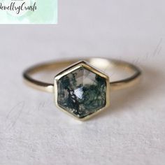 a close up of a ring with a stone in the center on a white surface