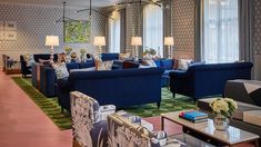 a living room filled with blue couches and chairs next to windows covered in curtains