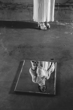 a black and white photo of someone's feet in front of a mirrored surface