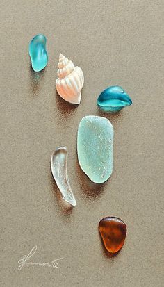 five different colored sea glass pieces on the sand with one shell in the foreground