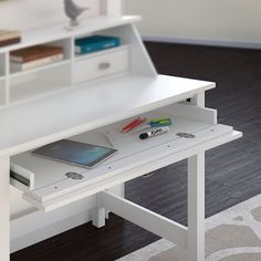 a white desk with a laptop and other items sitting on it's top shelf