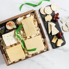 an assortment of cheeses and crackers in a box on a marble countertop