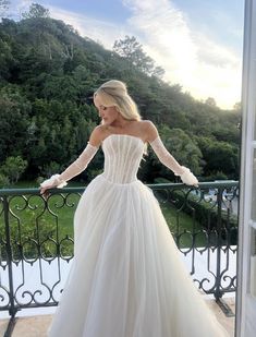 a woman in a wedding dress standing on a balcony