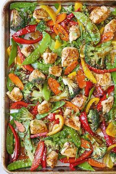 a pan filled with chicken, peppers and broccoli on top of a table