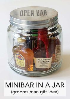 a jar filled with miniature liquor bottles on top of a white table next to a sign that says, minibar in a jar grooms man gift idea