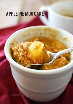 an apple pie mug cake in a white bowl with a spoon and red napkin next to it