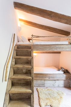 a wooden bunk bed sitting in the middle of a room next to a stair case