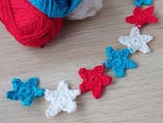 red, white and blue crochet stars are on the table next to yarn