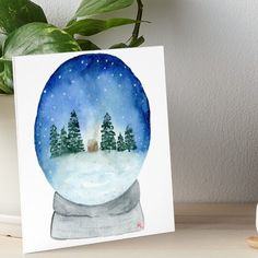 a watercolor painting of a snow globe with trees in it and a house inside