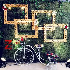 a bike is parked in front of a wall decorated with flowers and frames for photos