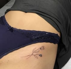 a woman's stomach with a small tattoo on her lower back and flowers in the side