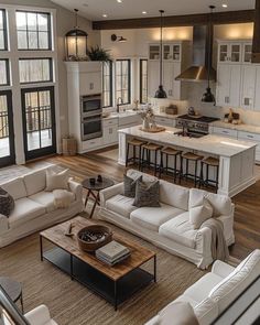 a living room filled with furniture next to a kitchen and dining room table in front of an open floor plan