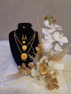 necklaces and flowers on display in front of a black mannequin with white flowers